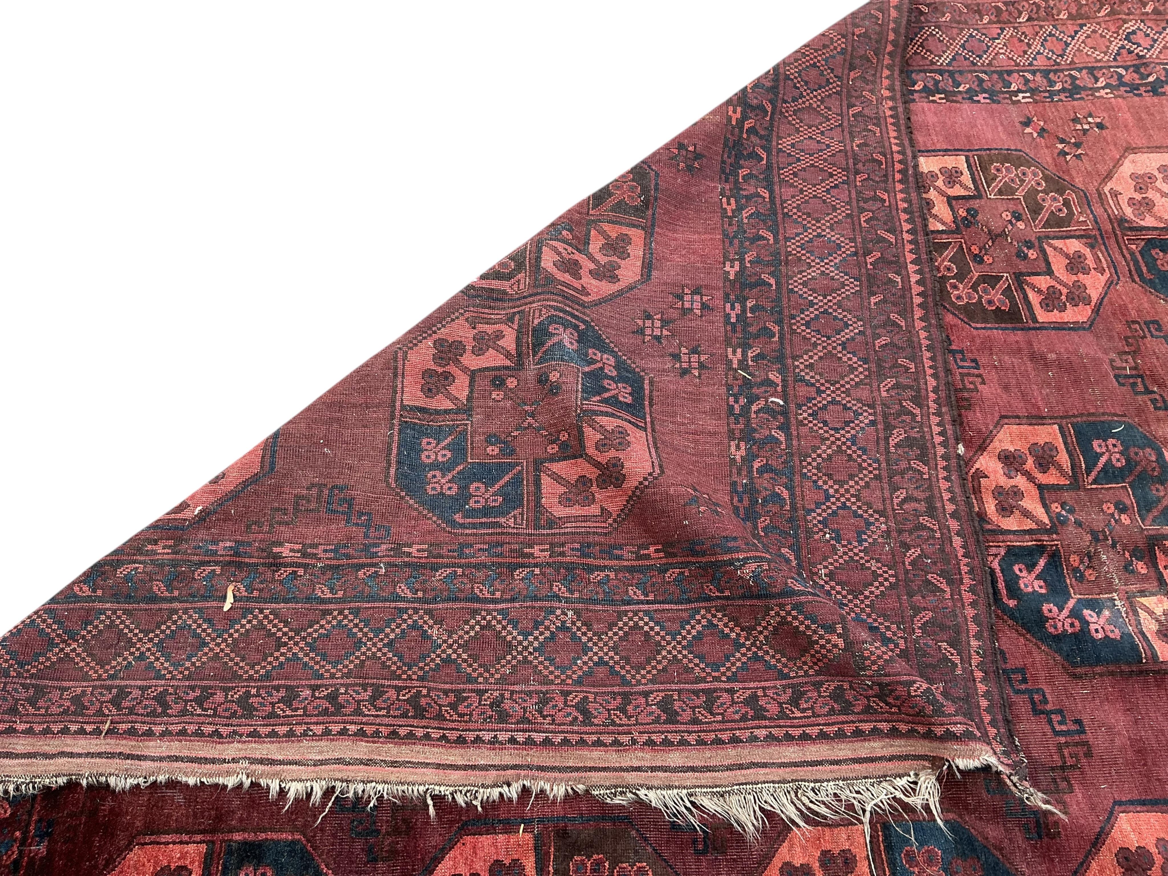 An Afghan burgundy ground carpet, 375 x 230cm
